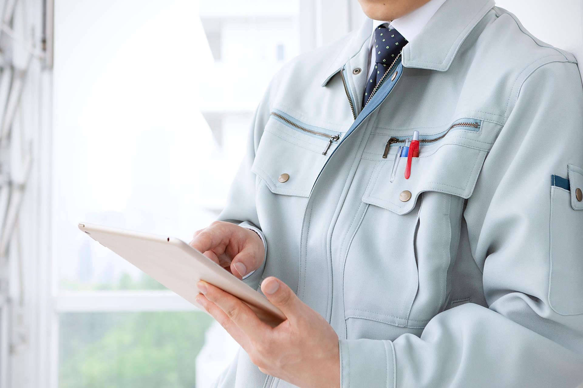 バインダーを指さす作業服の人の画像